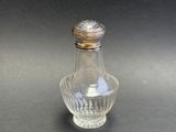 a small glass bottle with a silver lid on a table