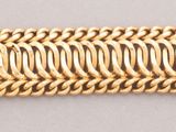 a close up of a gold bracelet on a white surface