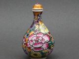 une image représentant un vase coloré orné de fleurs, posé sur une surface grise