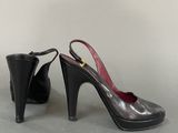 pair of women ' s black high heel shoes on a gray surface