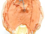 orange frosted donut with a spider on top on a white surface