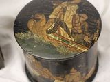 a black box with a painting on it next to a candle