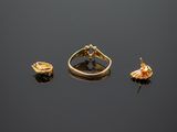 two gold rings and a ring with a flower on top of a black surface