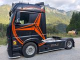 a black semi truck with an orange design on the side
