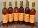 six bouteilles de vin sont alignées sur une table