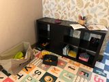 a room with a carpet, a book shelf, and toys on the floor