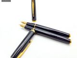 deux stylos à plume noirs et dorés posés l'un à côté de l'autre sur une surface blanche