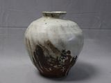 a white and brown vase sitting on a gray surface
