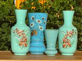 trois vases posés sur une table devant un buisson