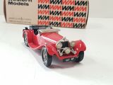a red toy car sitting on a table next to a box