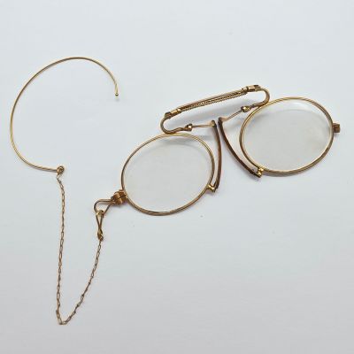 une paire de lunettes et une chaîne posées sur une surface blanche
