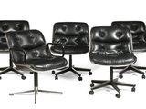 quatre fauteuils de bureau en cuir noir posés sur des roulettes, sur une surface blanche