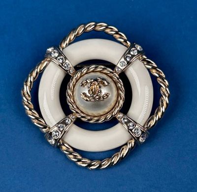 a close up of a white and gold broochle on a blue background