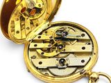 a gold pocket watch that is open on a white surface