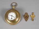 a small gold pocket watch and a cross on the table