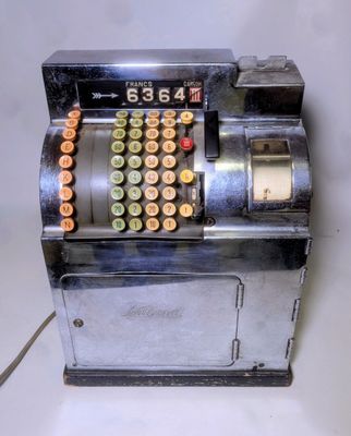 une caisse enregistreuse à l'ancienne sur laquelle sont posées de nombreuses pièces de monnaie