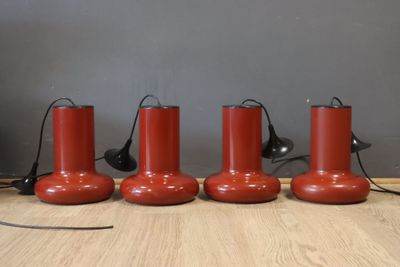 quatre lampes rouges posées sur un plancher en bois, près d'un mur