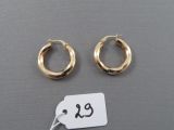 deux paires de boucles d'oreilles créoles en or, avec une étiquette de prix posée sur une surface grise