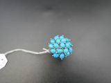 un gros plan d'une bague ornée de perles bleues sur une surface noire