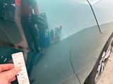 a person holding a measuring tape next to a car