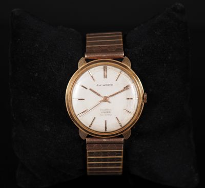 a close up of a gold watch on a black cushion