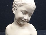 a small white statue of a child on a black surface