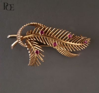 un gros plan sur une broche en feuille d'or sertie de pierres roses