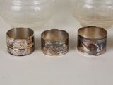 four different types of silver rings and a vase on a table