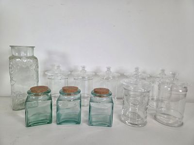 many glass jars and jars with cork lids on a table