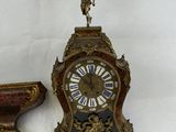 a small clock sitting next to a vase on a table