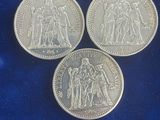 three silver coins sitting on top of a blue cloth