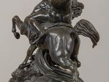 statue of a man riding a horse on a rock in front of a white wall