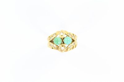 un gros plan d'une bague en or sertie de deux pierres vertes
