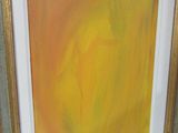yellow and orange painting in a gold frame on a green wall