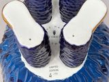 three pairs of shoes sitting on top of a blue vase