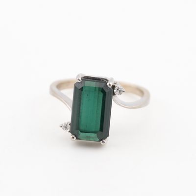un gros plan d'une bague en tourmaline verte sur fond blanc