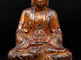 a wooden statue of a buddha sitting on top of a table