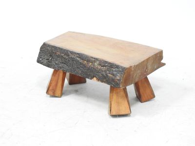 un petit banc en bois fabriqué à partir de rondins, posé sur une surface blanche