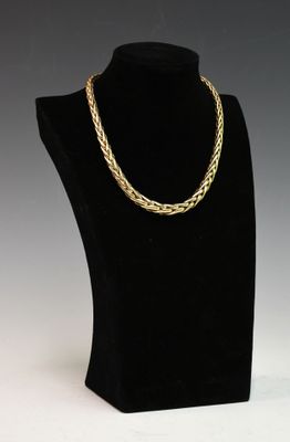 un collier à chaîne en or posé sur un présentoir noir pour mannequin