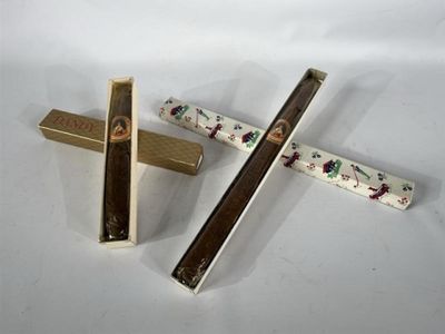 deux bâtonnets en bois et une boîte posés sur une surface blanche