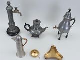 five different types of silver teapots and a brass bell