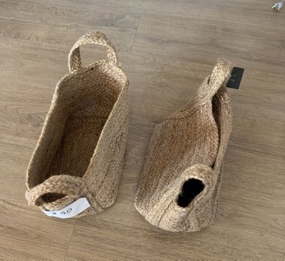 une paire de pantoufles en jute naturel posées sur un parquet, avec une étiquette de prix