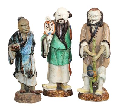 trois figurines représentant des hommes asiatiques debout les uns à côté des autres