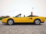 yellow sports car parked on cobblestone parking lot with sky in background
