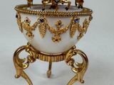 a gold and white egg with a carousel on it