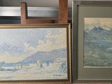 two framed paintings on a shelf next to a chair