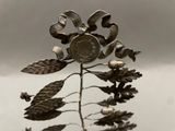 a metal sculpture of a flower with a coin on it