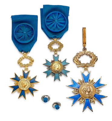 trois médailles et une médaille sont exposées sur un support blanc