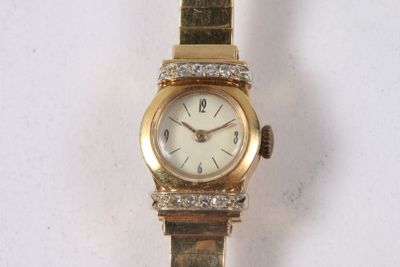 une montre en or sertie de diamants, posée sur une surface blanche
