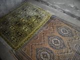 two rugs on the floor in the corner of a room